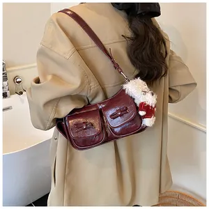 Detail der burgunderroten glänzenden PU-Umhängetasche mit Taschen und Plüschanhänger