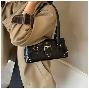 Close-up of black glossy leather underarm bag with silver rivets and metal rings