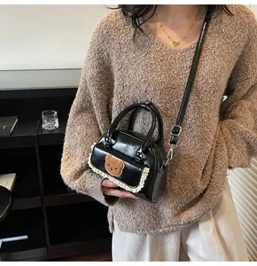 Detailansicht der kleinen schwarzen Lackleder-Tasche mit Bären-Patch und weißer Spitze