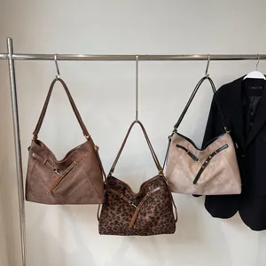 Vintage tote bags in brown suede, leopard print, and beige on a metallic display stand