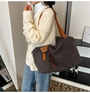 Detail of dark brown plush fleece tote bag with bear charm and soft leather strap