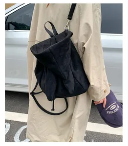 Détail d'un sac à dos en daim noir avec design à capuche et fermeture à cordon sur l'épaule