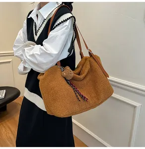 Detail of a brown plush tote bag featuring a cute bear pendant and leather shoulder strap