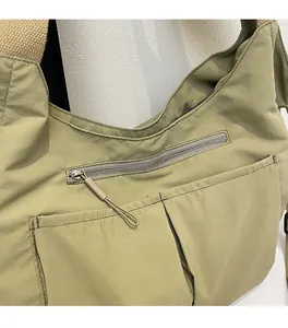 Detail of light green nylon bag showing soft fabric texture and functional front pockets