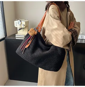 Detail of black fleece tote bag with brown leather straps and cute bear charm accessory