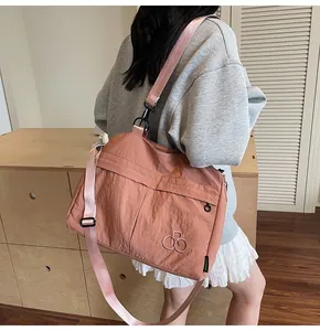 Detail of salmon pink nylon tote bag showing front zipper pocket and adjustable strap
