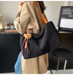 Detail of black faux shearling tote bag with leather strap and cute bear charm