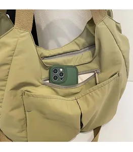Detail showing the multi-pocket structure and khaki nylon material of the tote bag