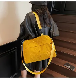 Detail of the bright yellow shoulder bag featuring crinkled texture and bike embroidery