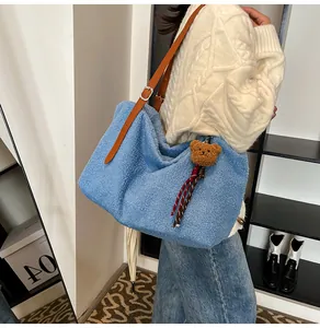 Close-up of blue faux shearling hobo bag with brown leather strap and bear charm