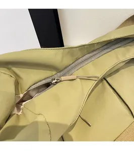 Detail view of smooth metal zipper and long cord puller on green nylon dumpling bag