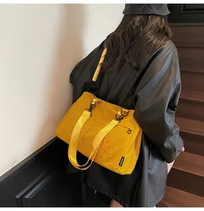 Detail of yellow nylon tote bag with embroidery logo and black metal zipper closure