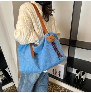 Close-up of blue fuzzy tote bag with brown leather strap and cute bear charm detail