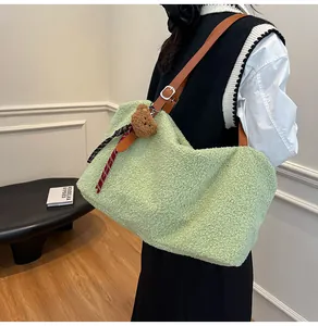 Detail of light green fleece tote bag featuring brown leather strap and bear charm