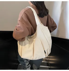 Detail of a large beige nylon crossbody bag featuring a woven brand tag on the side