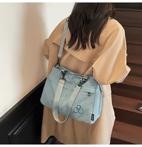 Rear view of a light blue large nylon tote bag worn crossbody on wooden stairs