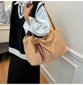 Detail of camel plush tote bag with long brown leather strap and cute bear charm