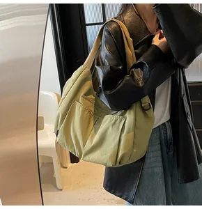 Detail of avocado green nylon dumpling bag showing functional multi-pockets and wide strap