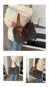 Detail view of dark grey plush tote bag with brown leather straps and bear charm