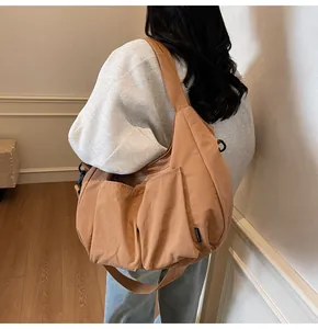 Brown nylon crescent bag detail showing large capacity side pockets and wide strap