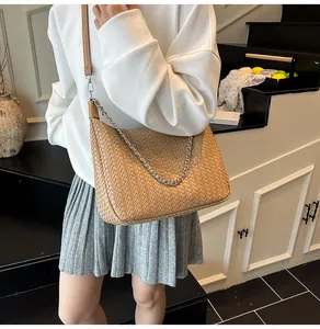 Détail du sac tressé marron clair avec chaîne argentée et bandoulière en cuir