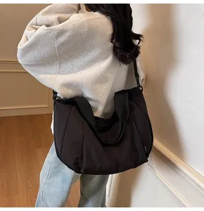 Close-up of black nylon dumpling bag with wide strap showing large capacity on model
