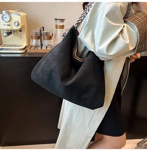 Détail du sac hobo matelassé noir avec bandoulière rayée porté à l'épaule du modèle
