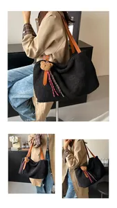 Close-up of black plush tote bag with leather straps and cute bear charm pendant