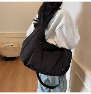 Rear view of a black large capacity nylon messenger bag with workwear style pockets