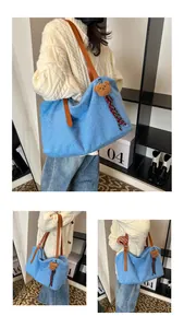Blue fleece tote bag with brown leather handles and a plush bear charm detail