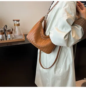 Détail du sac bandoulière tressé marron avec bandoulière en cuir et métal