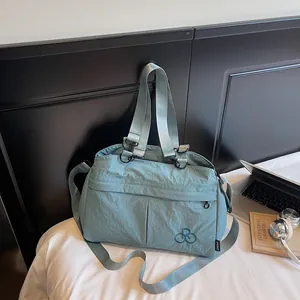 Detail of light blue nylon tote bag showing durable stitching and logo embroidery