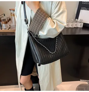 Détail du sac cabas tressé noir avec chaîne argentée et longue bandoulière réglable