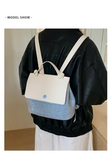 Model wearing a stylish contrast leather backpack with blue rhinestones and top handle