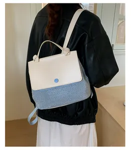 Detail of the chic contrast-color leather bag featuring shimmering rhinestones and knot handle