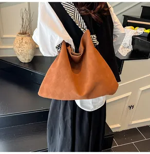 Gros plan d'un sac hobo marron texturé porté par un mannequin dans un décor minimaliste