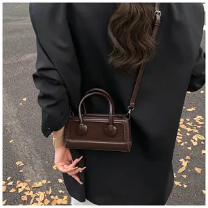 Detail of dark brown mini crossbody bag in suede and leather with round ornaments