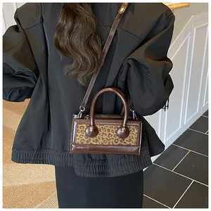 Detail of a brown leather shoulder bag with leopard print accent and dual handle