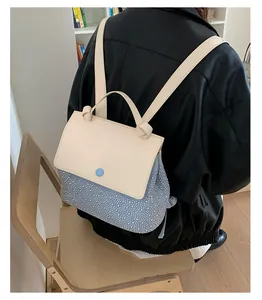 Detail of light blue rhinestone backpack with cream flap on a model in leather jacket