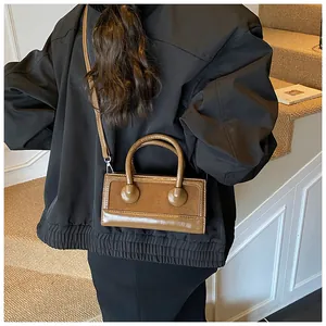 Close-up of vintage brown leather handbag with twin circular buckle details and strap