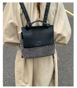Close-up of black backpack with silver rivet detailing and matte flap cover in street style
