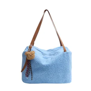Fashionable light blue plush tote bag with brown leather straps and bear pendant