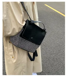 Close-up of contrast design with black leather flap and silver rivet detailing on handbag