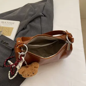 Vintage brown leather baguette bag with plush bear charm and woven rope detail