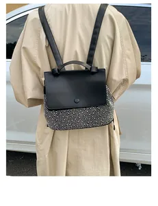 Detail of black leather backpack featuring silver rivet studs and elegant top handle