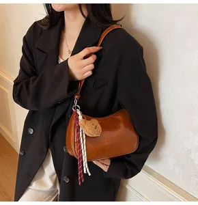 Detail of vintage brown shoulder bag with plush bear charm and embossed logo text