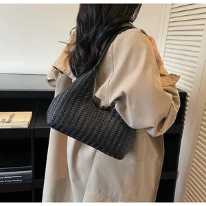 Gros plan sur la texture tressée noire et la forme en croissant de ce sac à bandoulière
