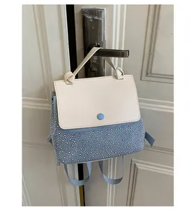 Detail of light blue and beige mini backpack with silver rivets hanging on a door handle