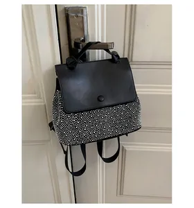Detail shot of black leather backpack with silver metallic studs and round buckle closure
