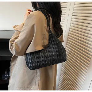 Détail de la texture en cuir tressé noir sur un sac porté épaule minimaliste
